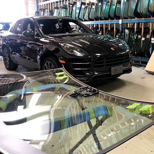 Speers Auto Glass Burlington technician replacing customer black SUV broken windshield inside the shop