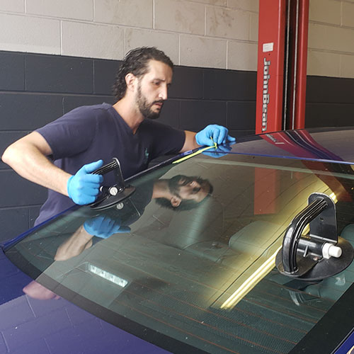 rear windshield techinician removing broken back glass and replace it with a new one by Speers Auto Glass