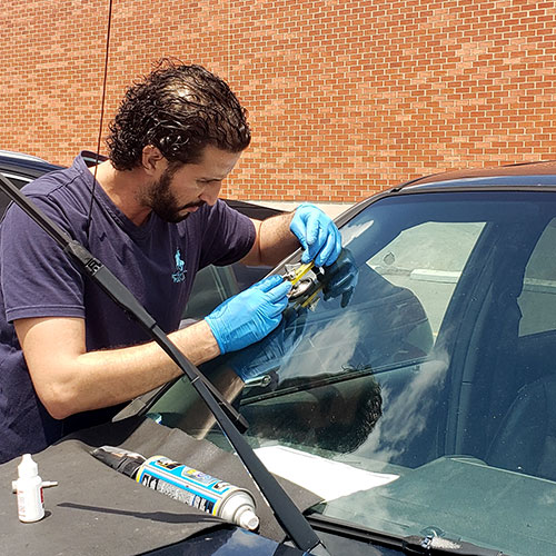 windshield technician Burlington repairing crack for customer car in parking lot by Speers Auto Glass